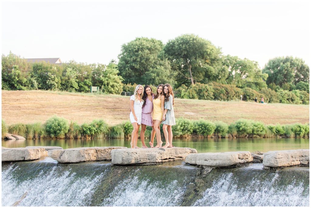 TCU girls standing on rocks by waterfall at the Trinity River.