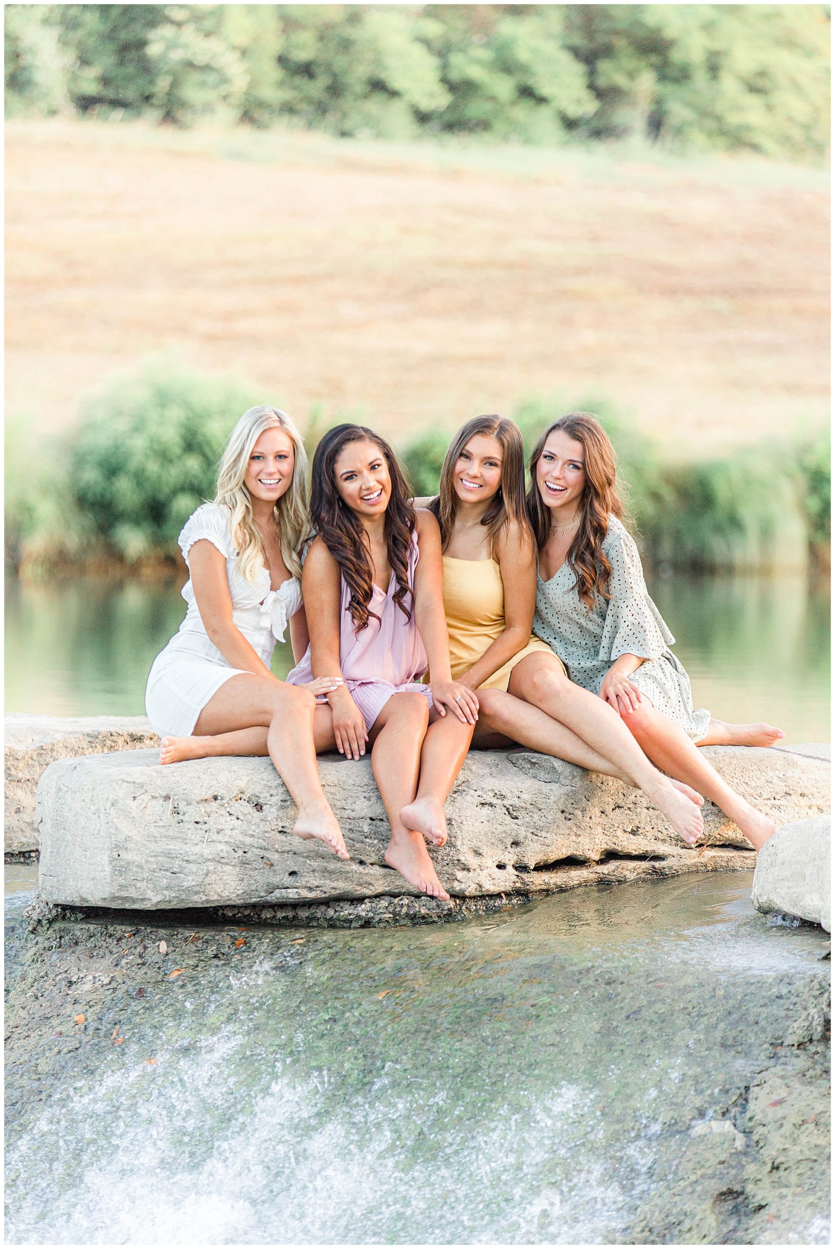 TCU girls seated on rocks by waterfall at the Trinity River.