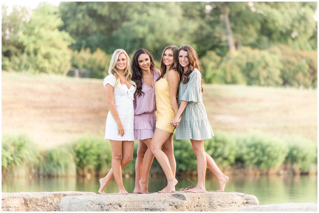 TCU girls standing on rocks by waterfall at the Trinity River.