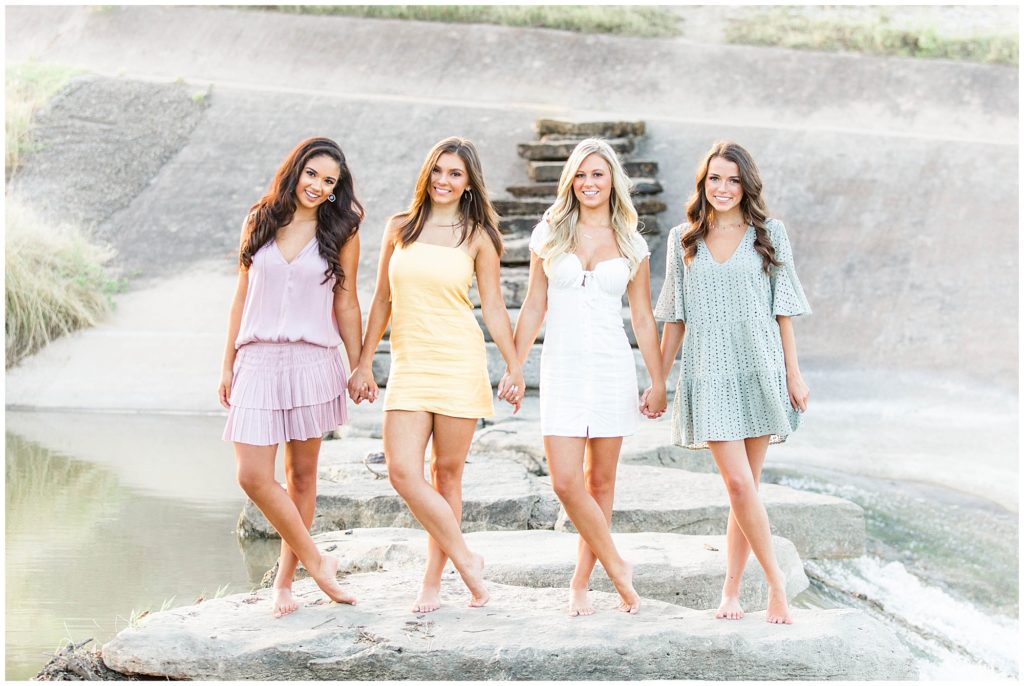 TCU girls standing with legs crossed 
by waterfall at the Trinity River.