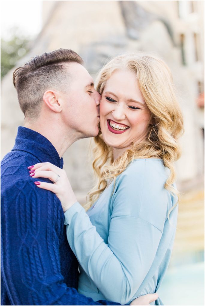 couple in blue outfits kissing for their adriatica village engagement photos