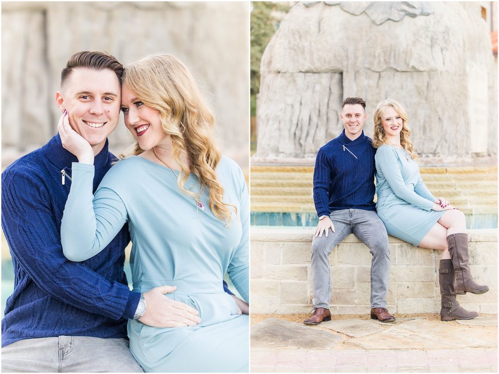 couple in blue outfits seated by fountain for their adriatica village engagement photos