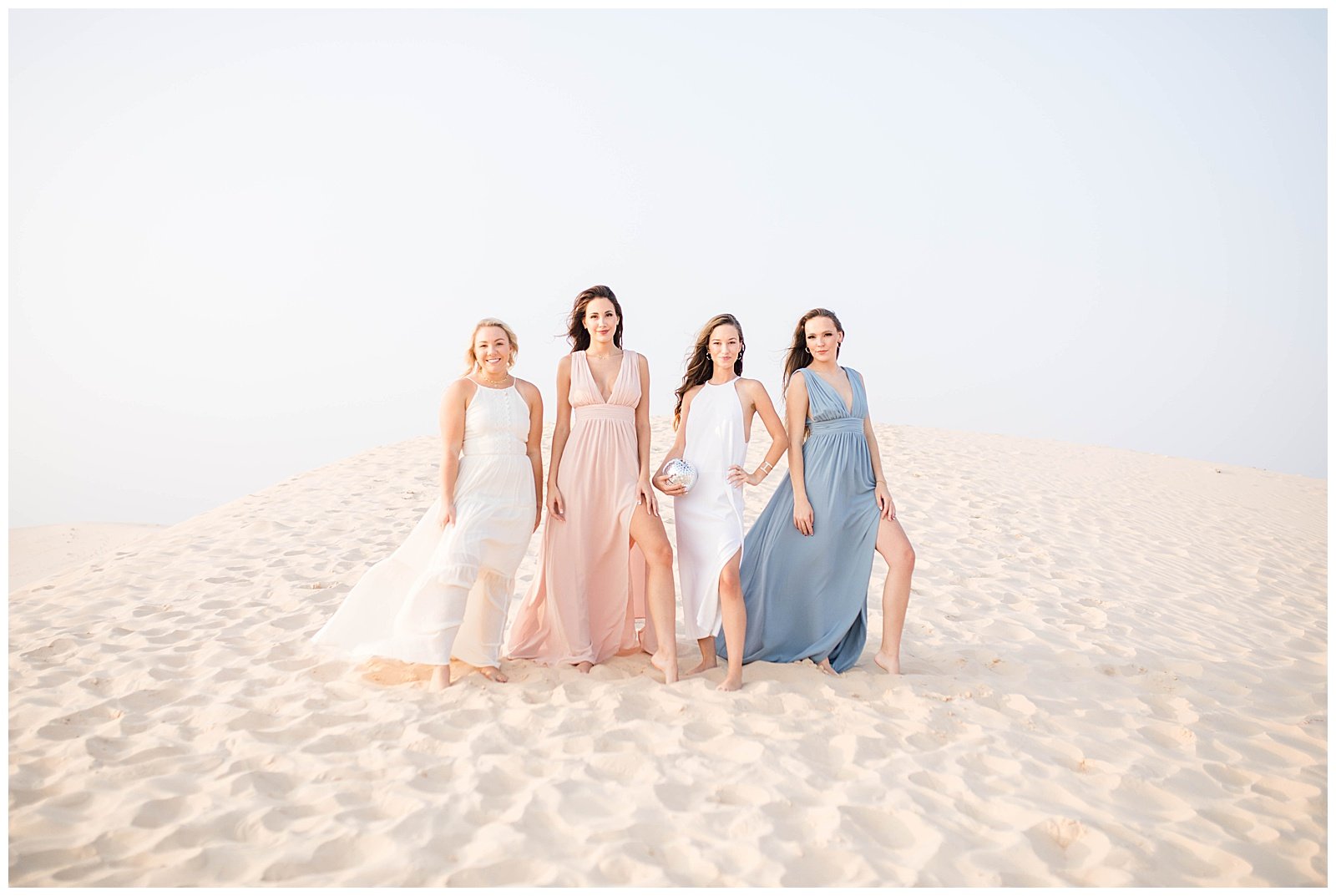 Four girls in pastel dresses posing at the sand dunes