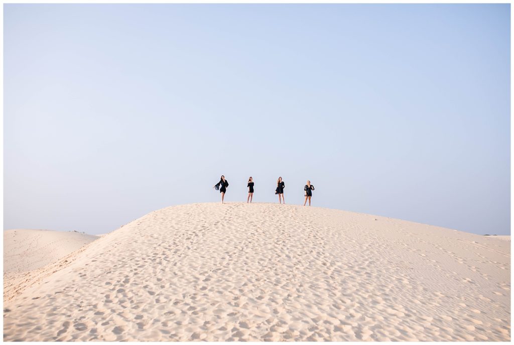 Four girls in black dresses posing at the sand dunes