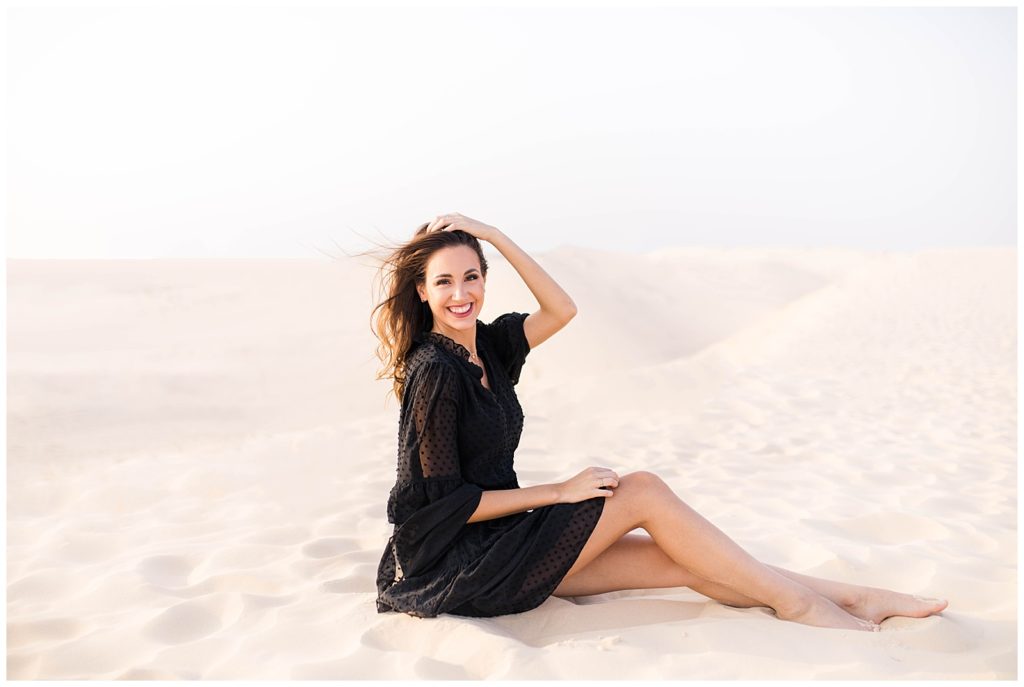 Girl sitting in the sand running her fingers through her hair